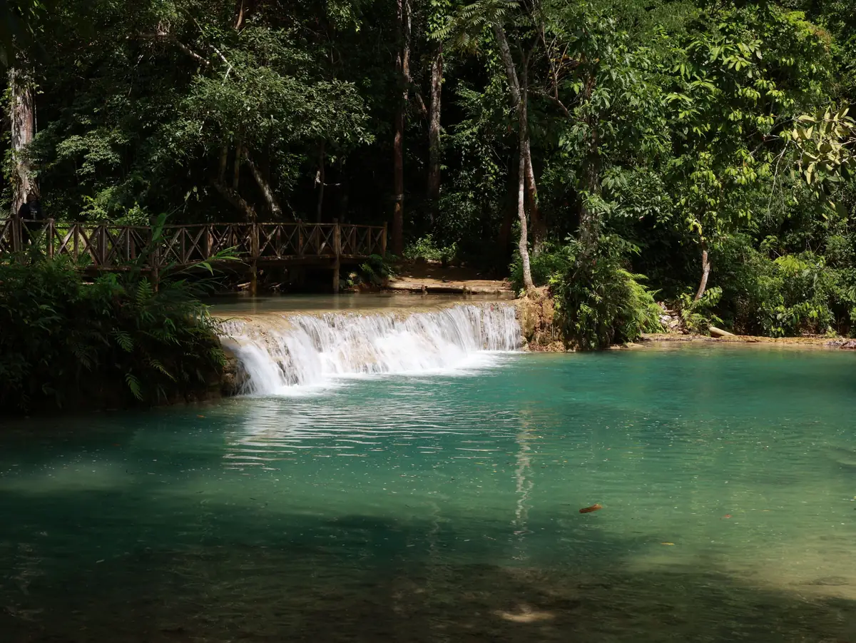 Turquoise tiered limestone pools cascading down through the forest at Kuang Si Falls